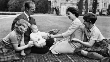 Britain's Royal family sits on blanket on the grounds of Balmoral Castle, Scotland, Sept. 8, 1960, during current holiday. Prince Andrew, in lap of his father, Prince Philip, reaches for trinket presented by his mother, Queen Elizabeth II, Princess Anne and Prince Charles try to catch the baby's attention. (AP Photo)